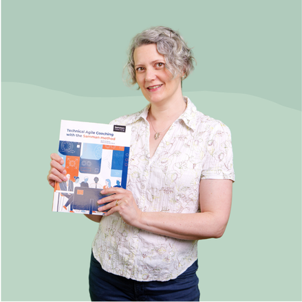 Emily Bache standing with her book Samman Coaching in her hands.